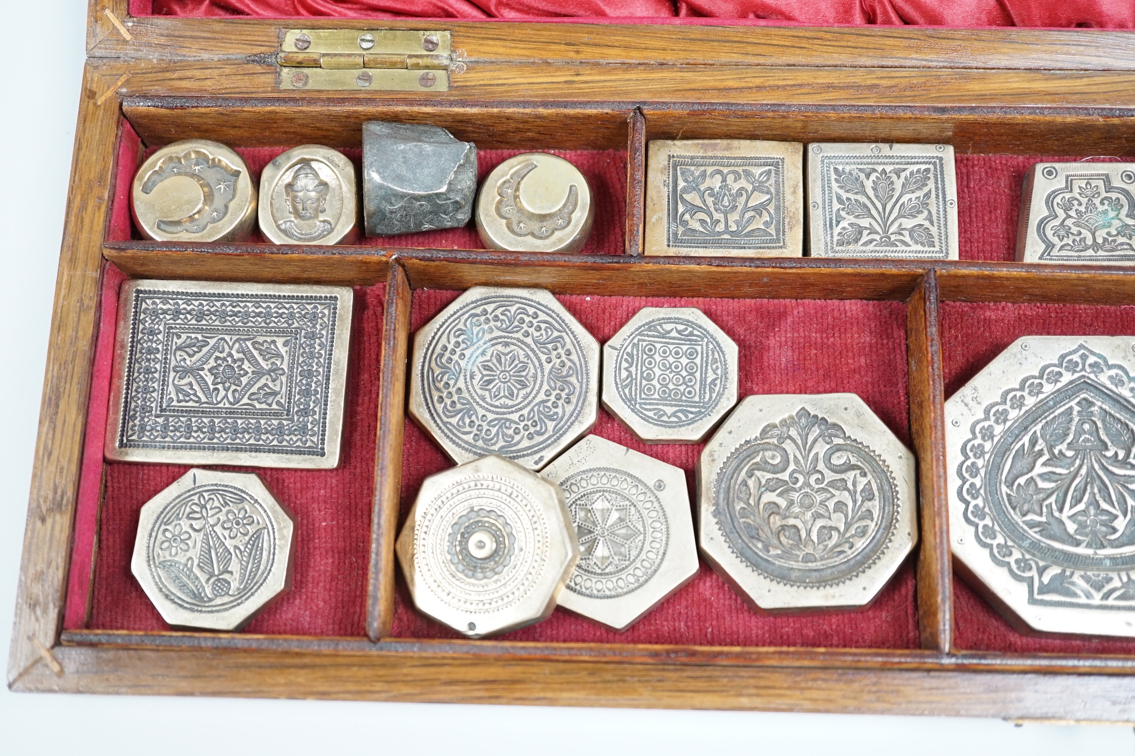 A cased group of Indian or Afghan brass seals or stamps, case 45.5cm wide, 14cm deep